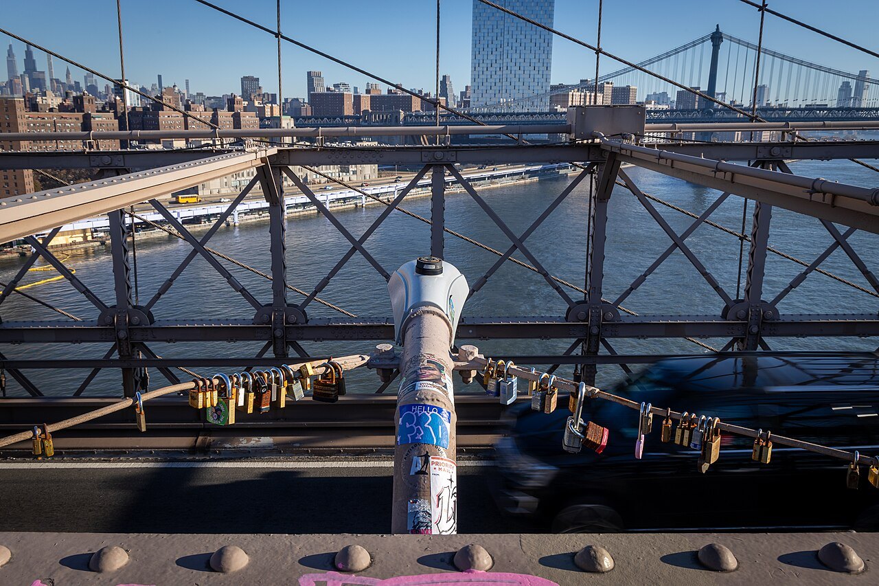 Padlocks on the bridge railings above the roadway, with the Manhattan Bridge beyond