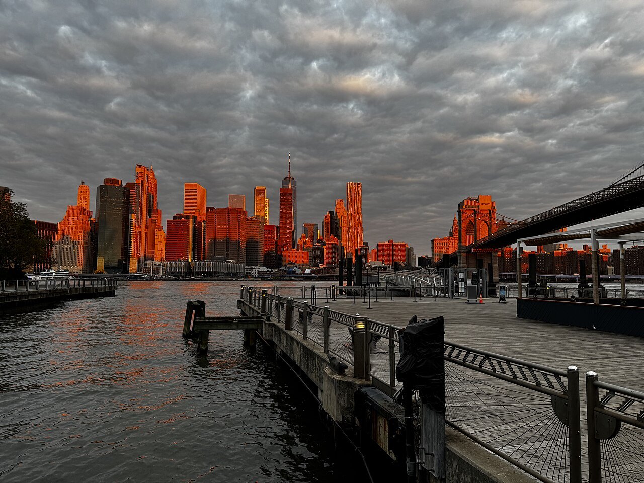 Lower Manhattan's towers lit orange at sunset from the Fulton Ferry Landing