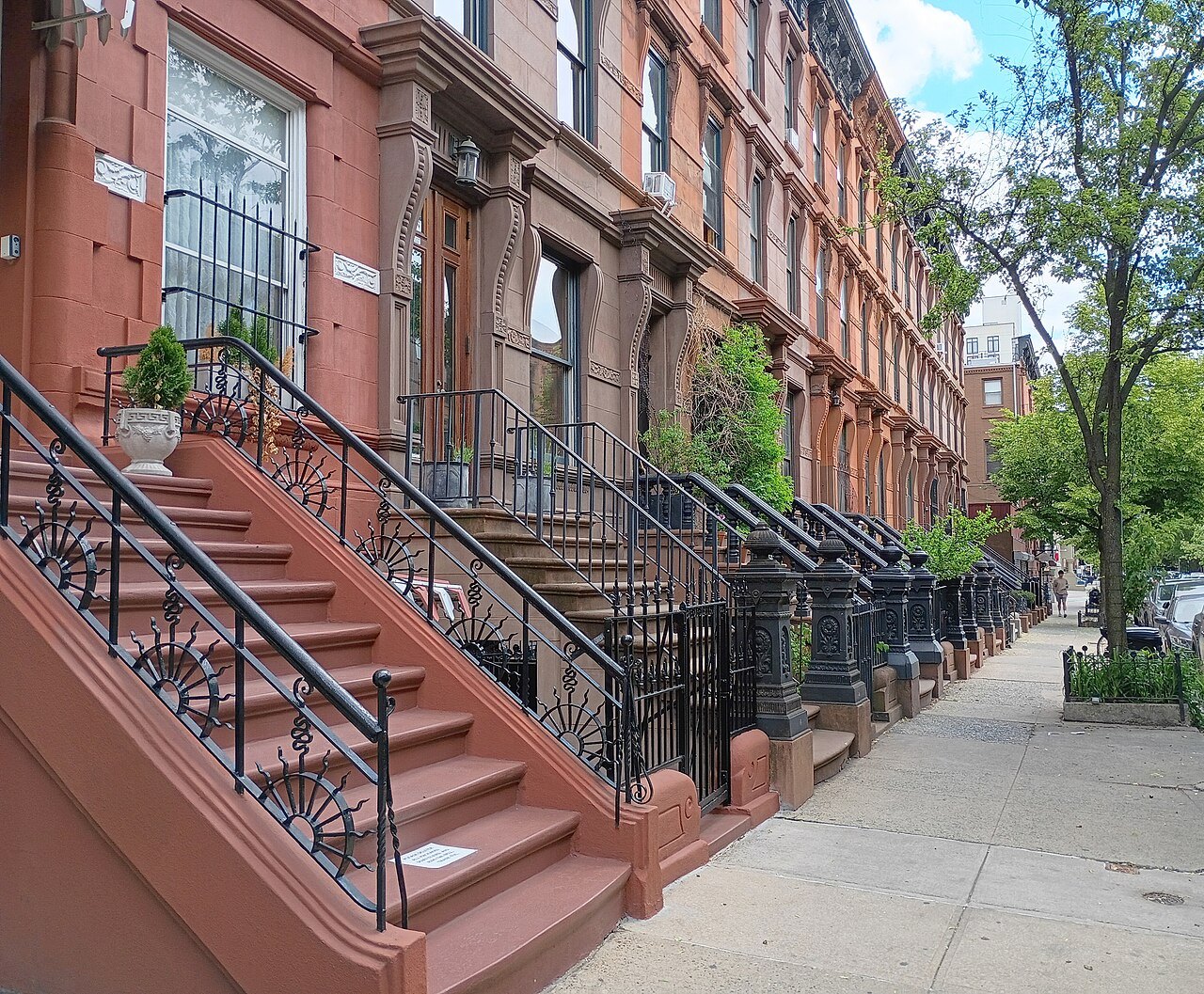 Brownstone stoops and iron railings along a Harlem street