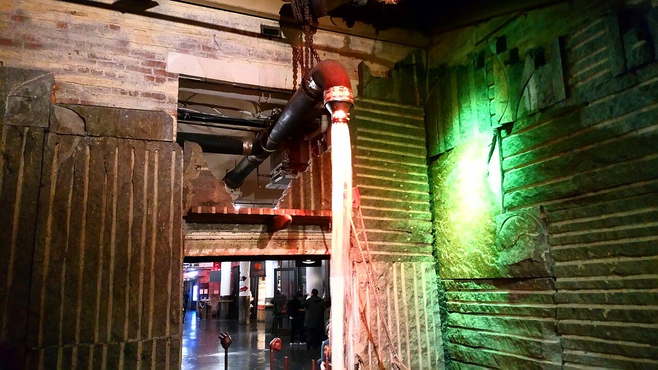 A green-lit pipe fountain in the brick corridor of Chelsea Market