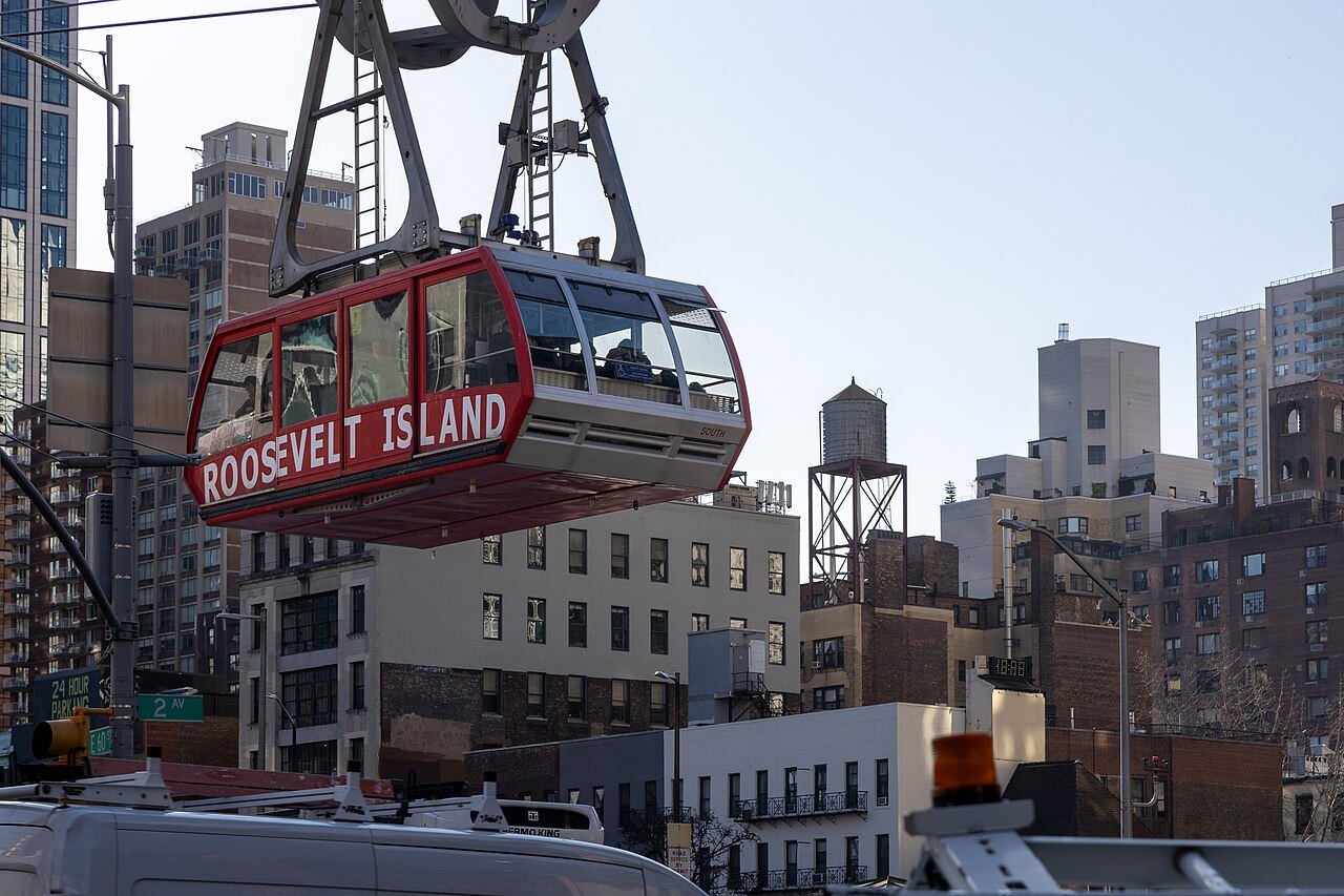 A red Roosevelt Island Tramway cabin over the streets of the East Side