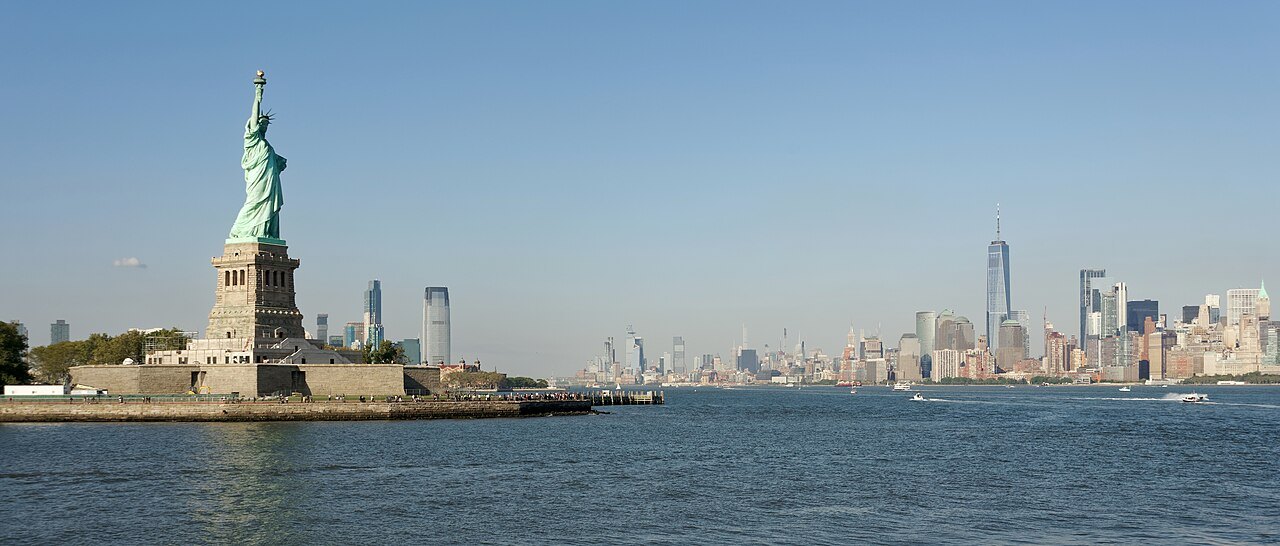 Liberty Island and the statue from the ferry, with Lower Manhattan across the harbor