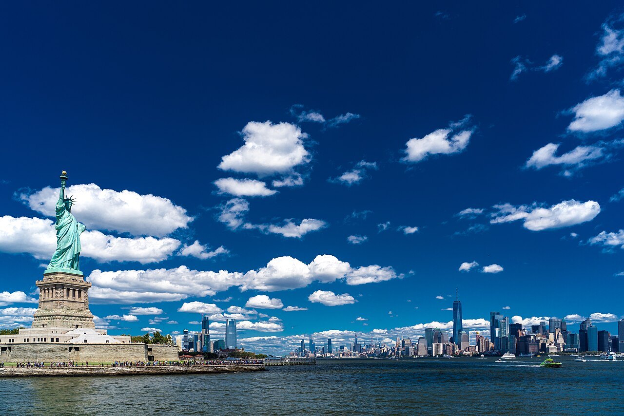 The Statue of Liberty under a deep blue sky, the skyline low behind