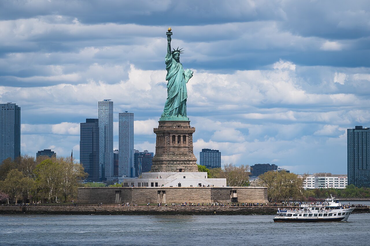 The Statue of Liberty with a sightseeing boat passing Liberty Island