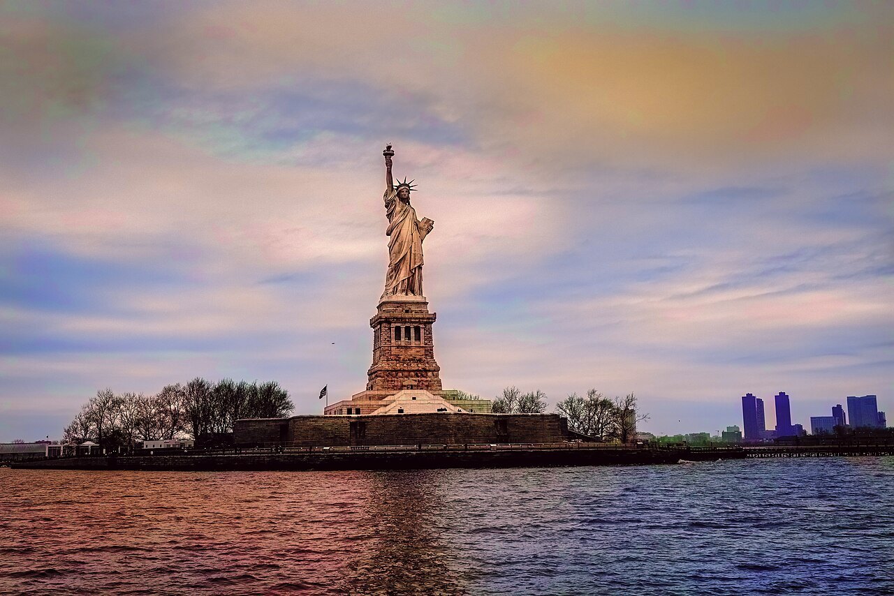 The Statue of Liberty against a pastel evening sky from the water
