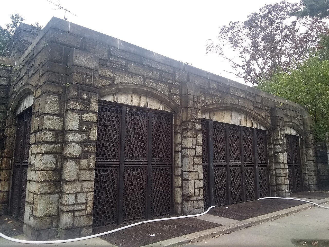 A stone gatehouse with carved wooden doors in Fort Tryon Park