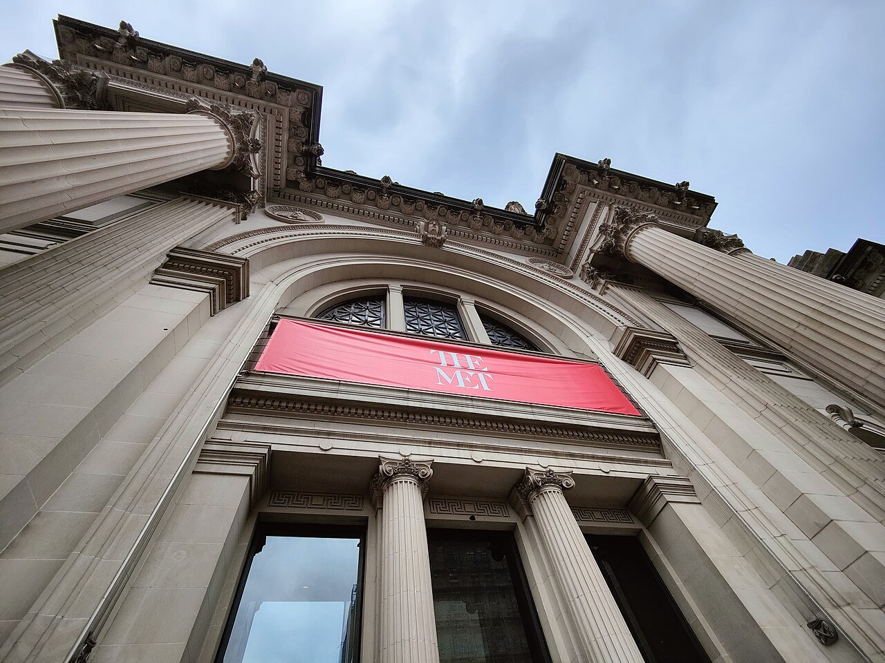 The Met's Fifth Avenue entrance seen from below, a red banner over the door