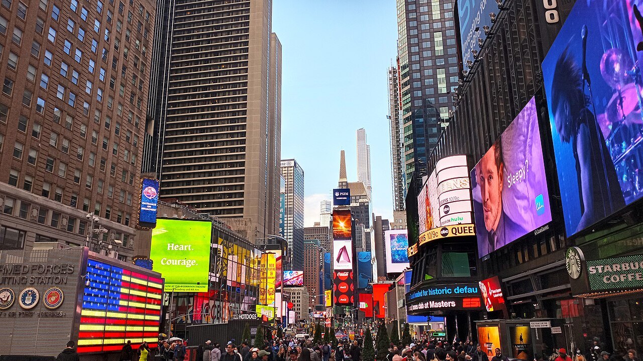 The screens and flags of Times Square on a bright afternoon