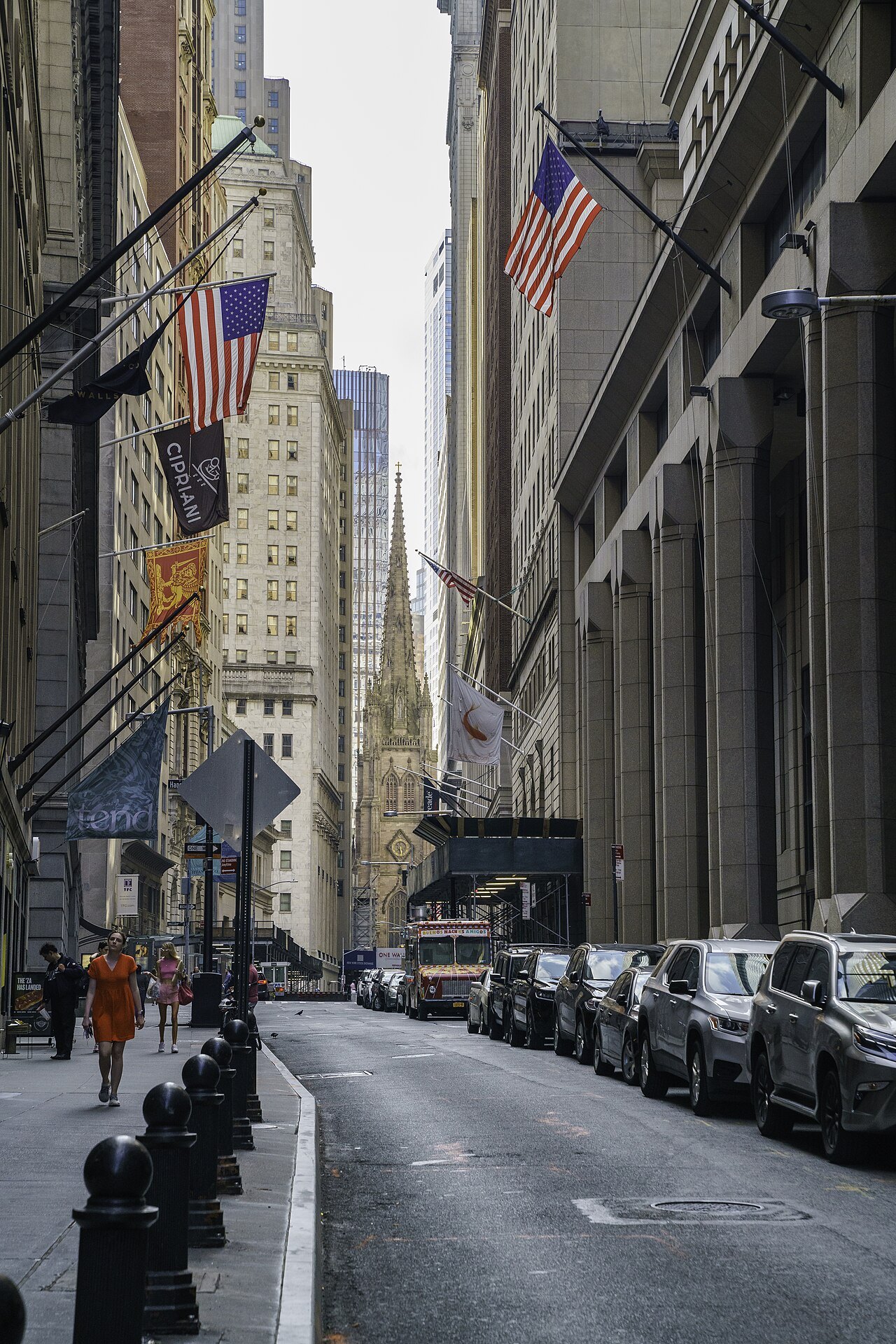 A quiet stretch of Wall Street in summer, parked cars along the curb